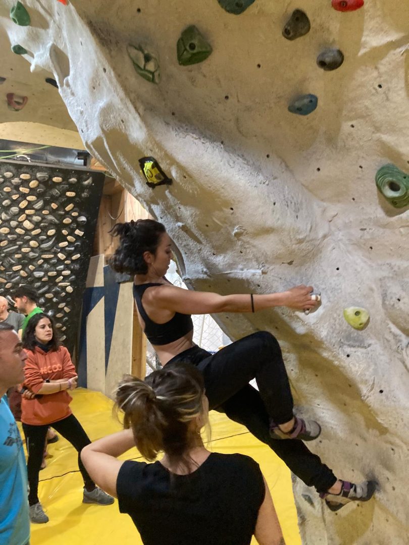 Alumna de un curso de escalada en un bloque con el técnico al lado